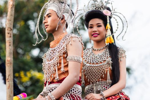 Two adults in ornate costumes celebrate the Kalasin Rocket Festival in Thailand, showcasing vibrant culture.