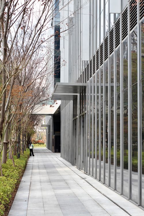 Free View of a modern office building in Shanghai, China, with glass facade and a person walking by. Stock Photo