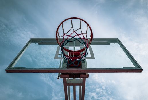 Dramatic upward angle of an outdoor basketball hoop against a blue sky in Trujillo, Peru.