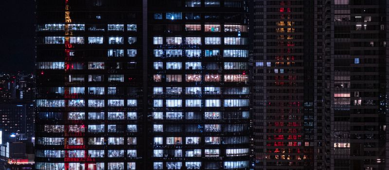 夜の東京の高層ビル群のガラス窓に街明かりが映り込み、大手損保の本社が立ち並ぶ都心の金融街を象徴するイメージ