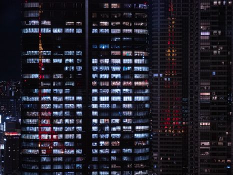 Night view of modern skyscrapers in Tokyo with reflective windows showcasing city lights.