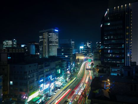 A bustling city street at night with dynamic light trails and illuminated skyscrapers in the urban landscape.