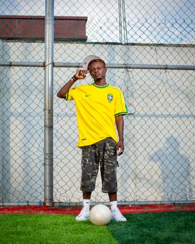 Young man in a Brazil football jersey standing on a soccer field. Vibrant and sporty outdoor portrait.