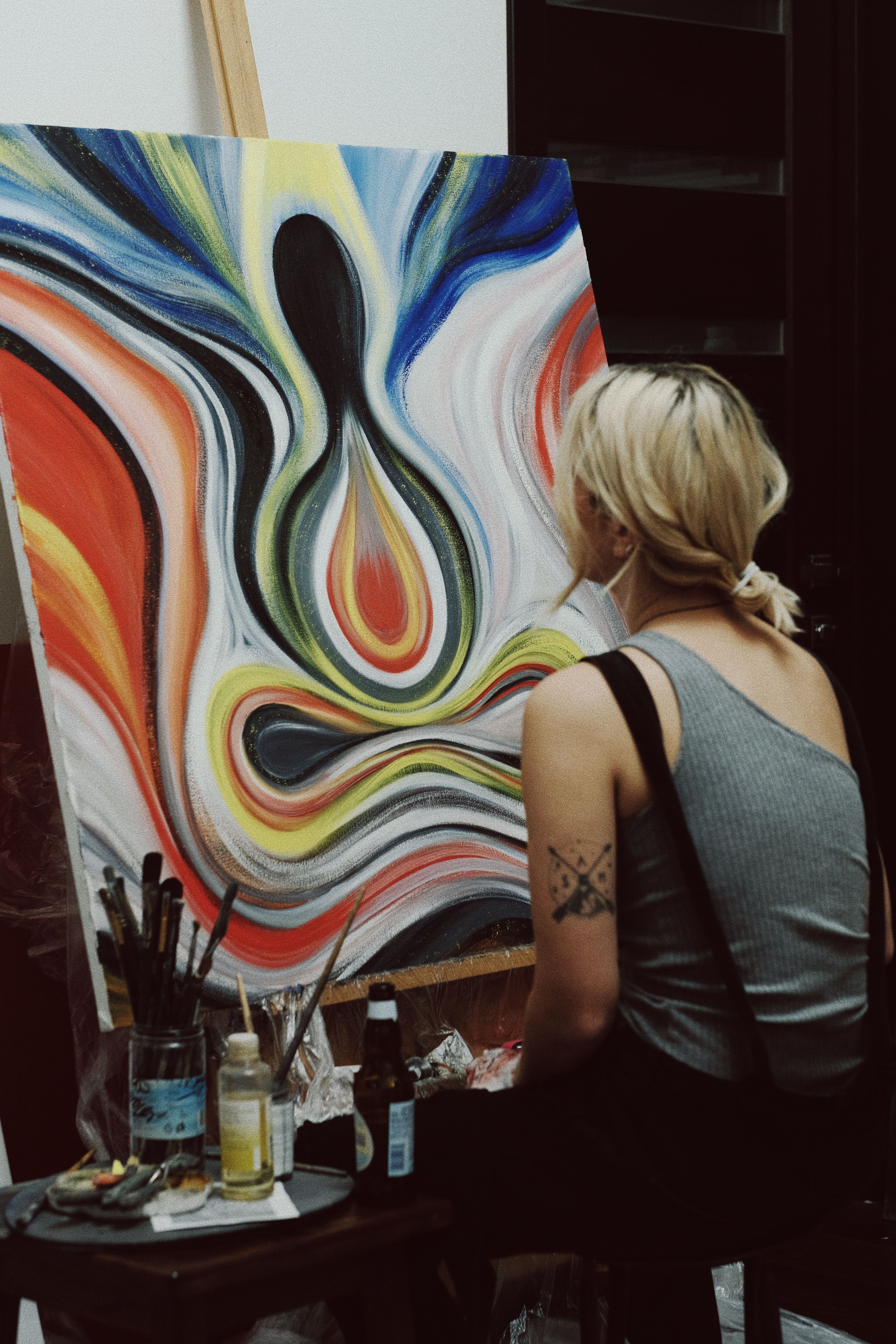 A female artist creates colorful abstract art in an indoor studio setting.