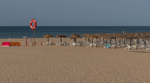 Free Peaceful Algarve beach with umbrellas and lifebuoy, capturing serene ocean view. Stock Photo