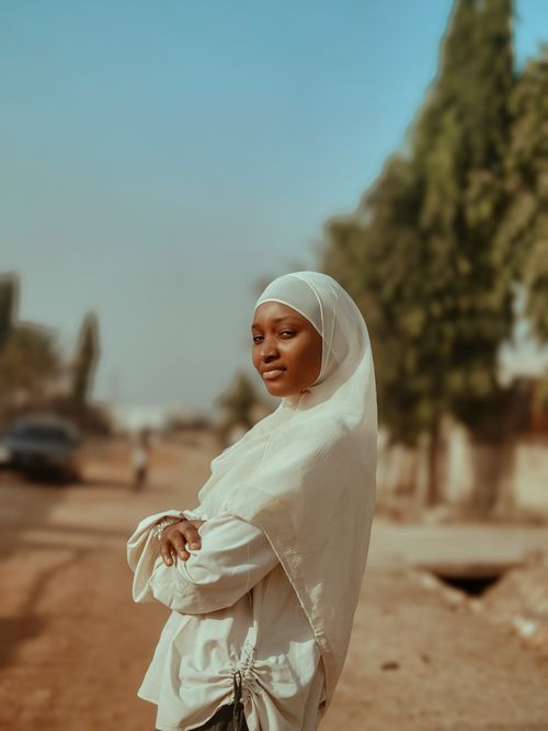 Free Portrait of a young woman wearing a hijab standing confidently on a sunny day outside. Stock Photo