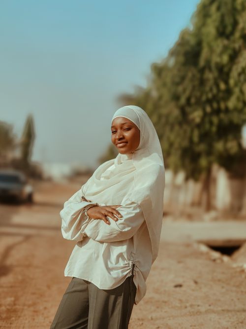 Free Young woman in hijab poses confidently on a sunny day street. Stock Photo