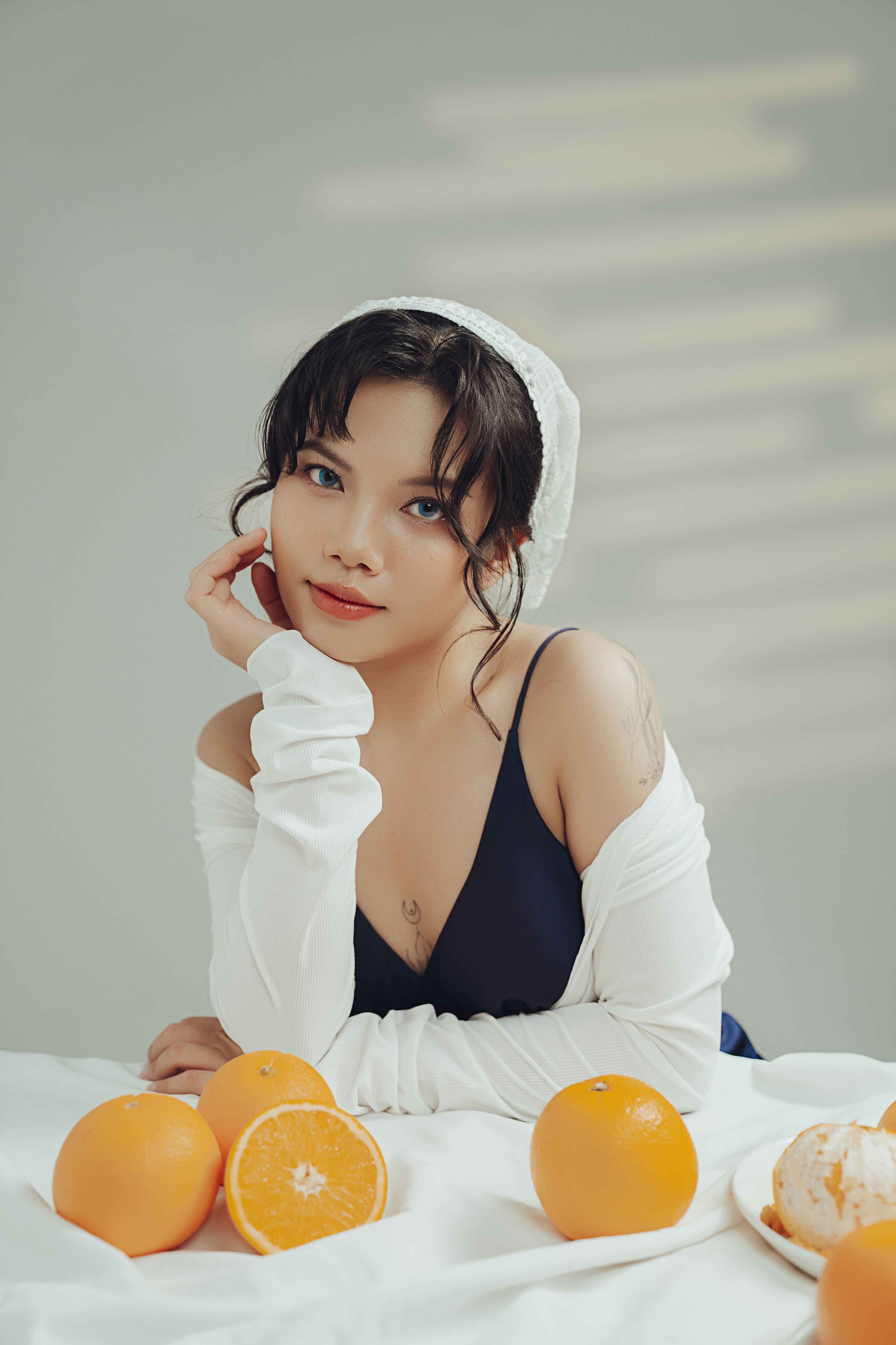 Portrait of a young woman with oranges, featuring natural light and a modern indoor setting.