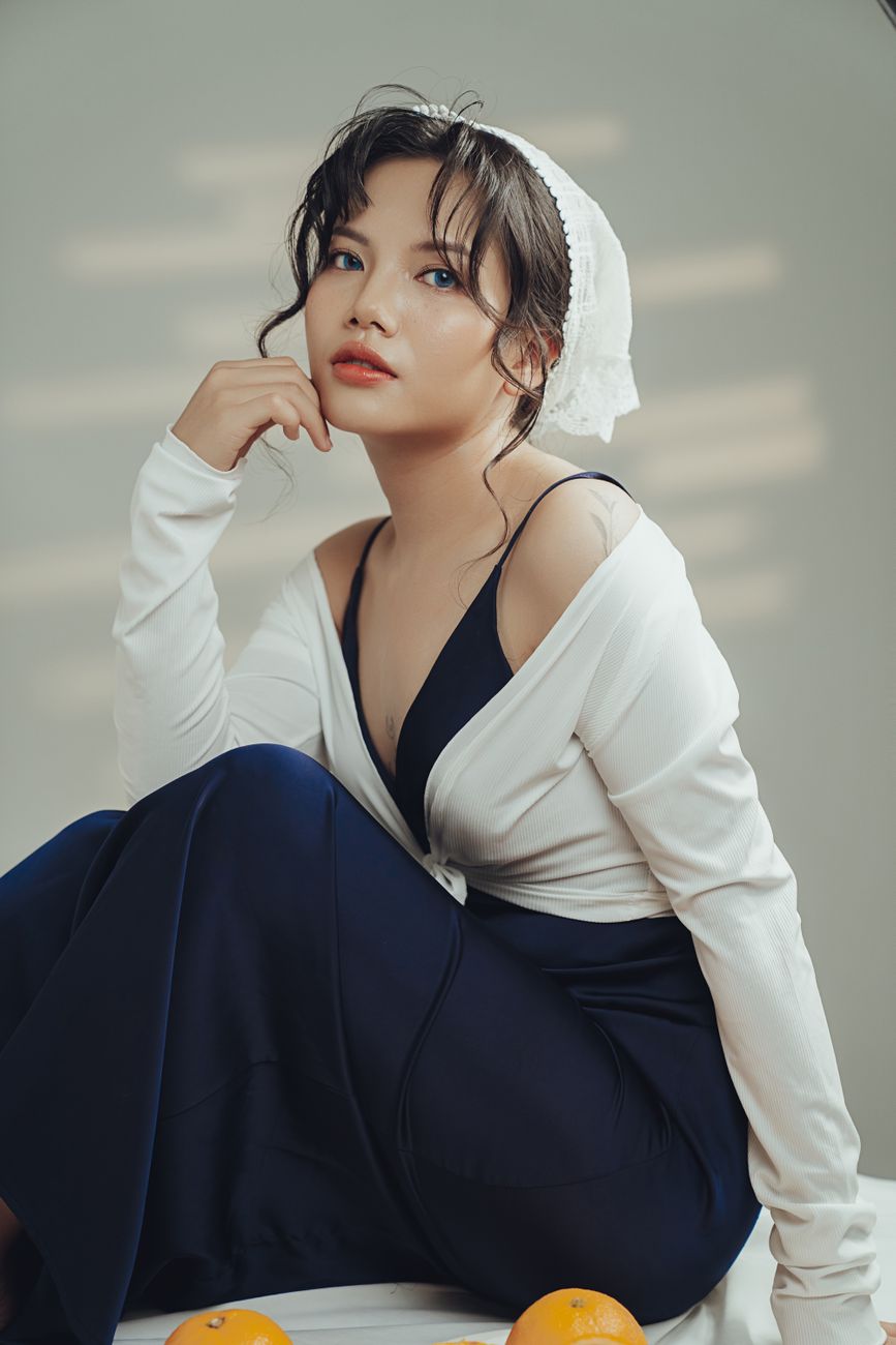 Stylish woman in fashionable clothing poses indoors with a dreamy look.
