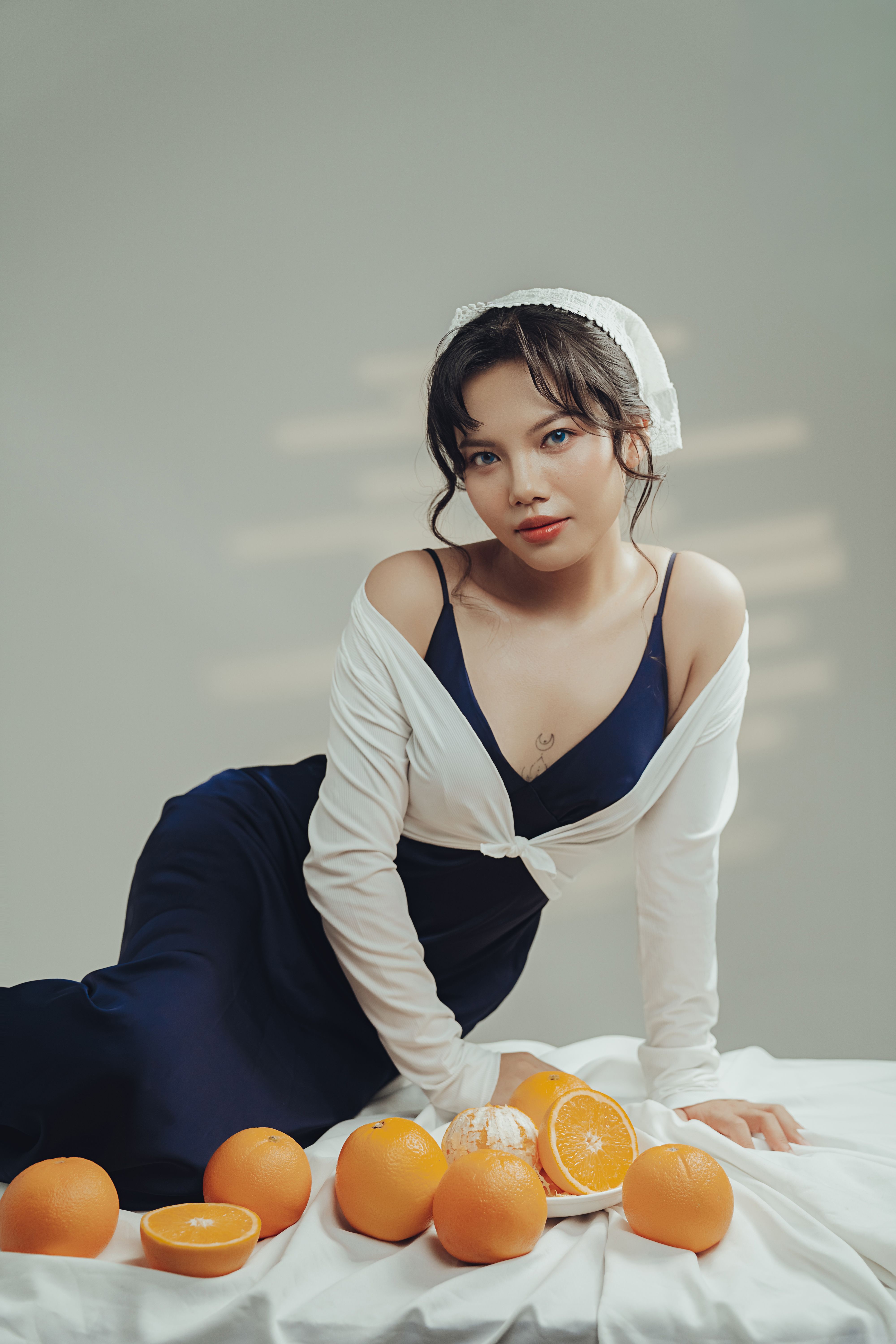 Elegant portrait of a woman in navy and white attire surrounded by fresh oranges.