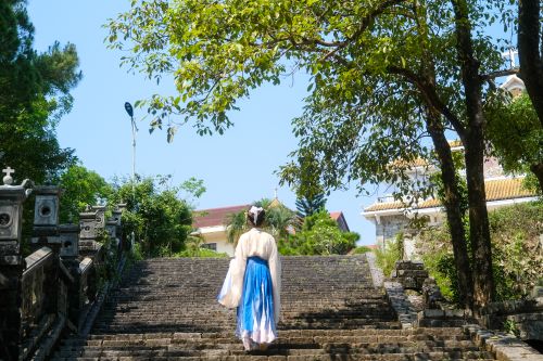 Free A woman in traditional dress walks up ancient steps in Hue, Vietnam. Stock Photo
