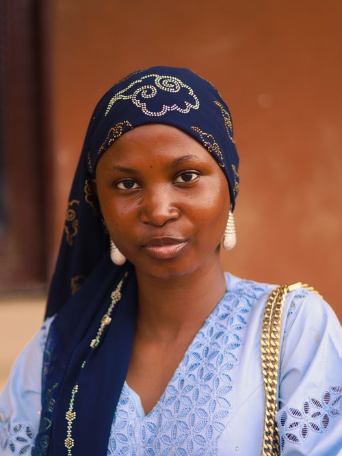 Free A woman wearing a blue headscarf and intricate lace dress, showcasing elegance and cultural fashion. Stock Photo