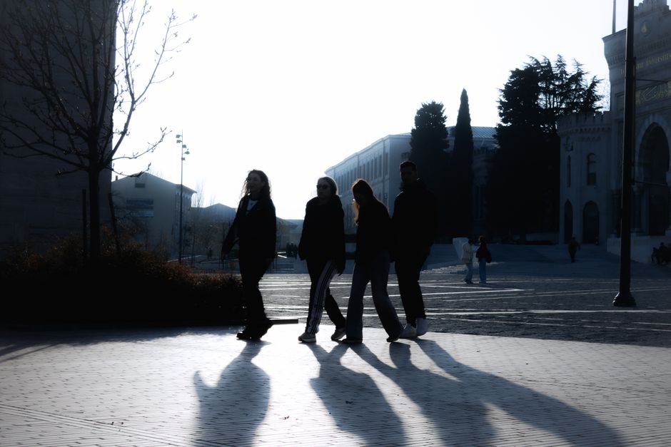 Silhouettes of four people walking in the early morning light on a street in Istanbul, Türkiye.