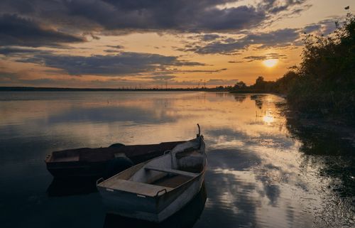 Free Peaceful autumn sunset with boats on a calm lake, reflecting the golden sky and surrounded by nature's tranquility. Stock Photo