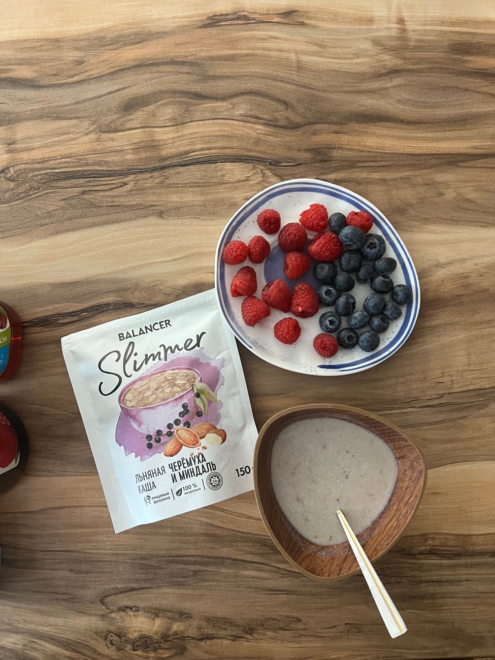 Top view of a berry smoothie in a glass beside a berry-filled breakfast spread.