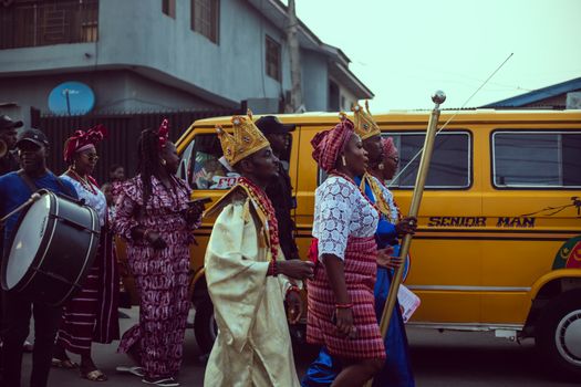 Vibrant cultural festival procession in Lagos, Nigeria, featuring traditional attire and drumming.
