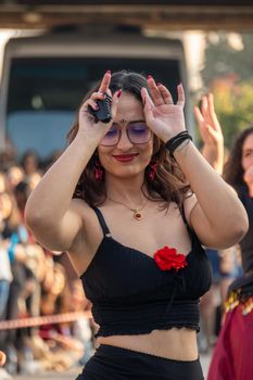 A woman joyfully dances outdoors wearing sunglasses, exuding happiness and style.