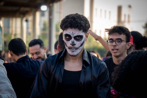 Free A crowd at an outdoor event with a prominent figure wearing Halloween-style skeleton face paint. Stock Photo