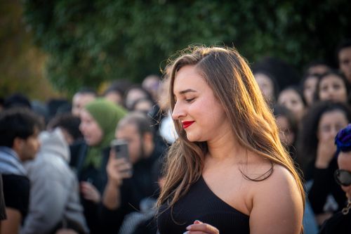 Free A young woman smiling in a crowd during an outdoor event with natural lighting. Stock Photo