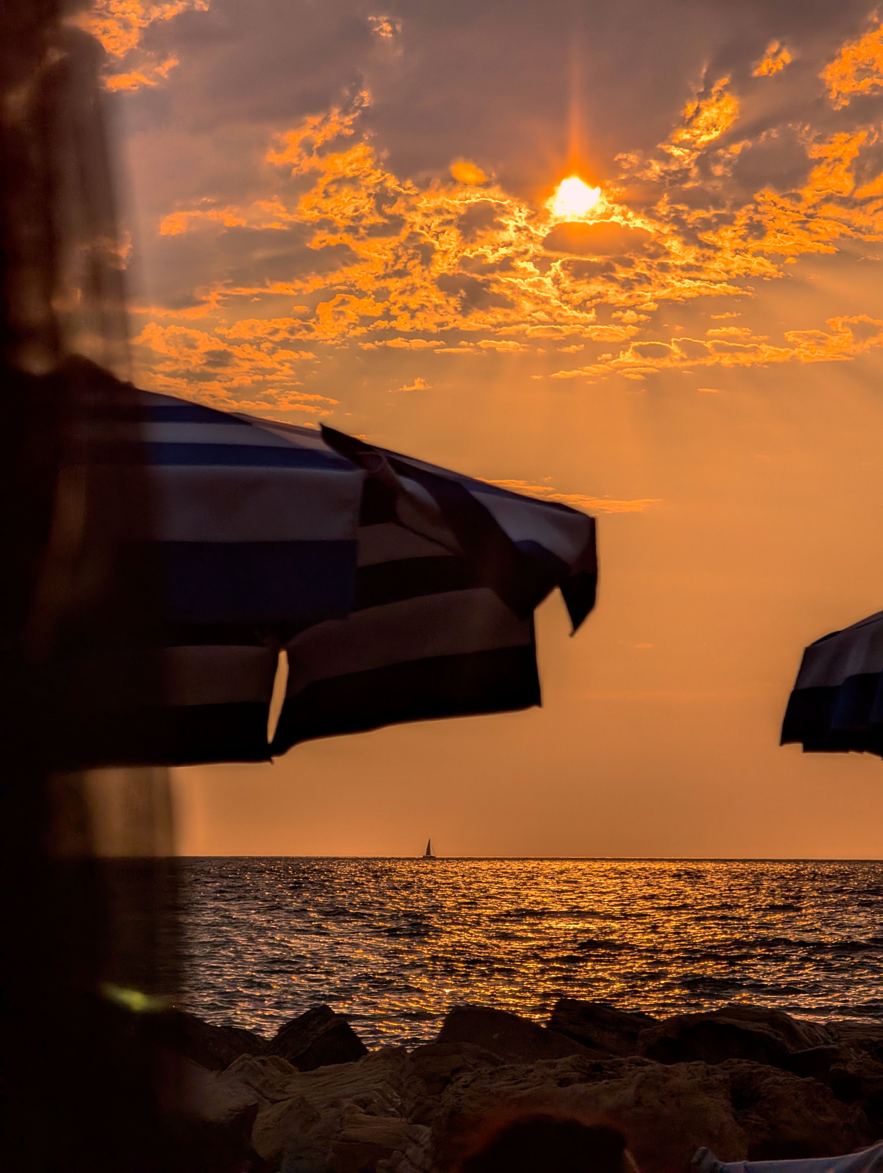 Beautiful sunset over the sea with umbrellas at Santa Maria di Castellabate, Campania, Italy.