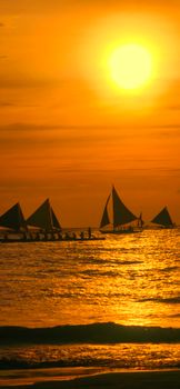 Stunning sunset over Boracay Island with traditional outrigger boats silhouetted against the golden sky.