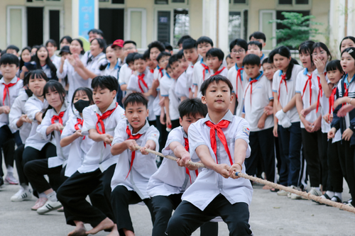 Free Group of children enjoying a lively tug of war game on a school playground. Stock Photo