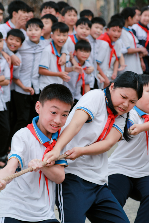 Free Energetic schoolchildren engaging in a lively tug-of-war during an outdoor event. Stock Photo