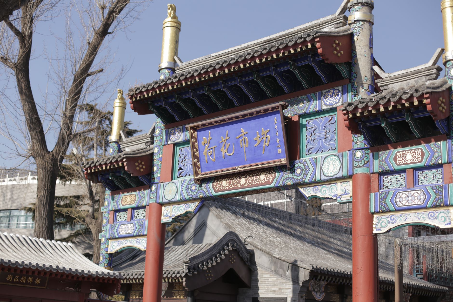 A beautifully ornate traditional Chinese gate under a clear blue sky, featuring intricate patterns and cultural decorations.