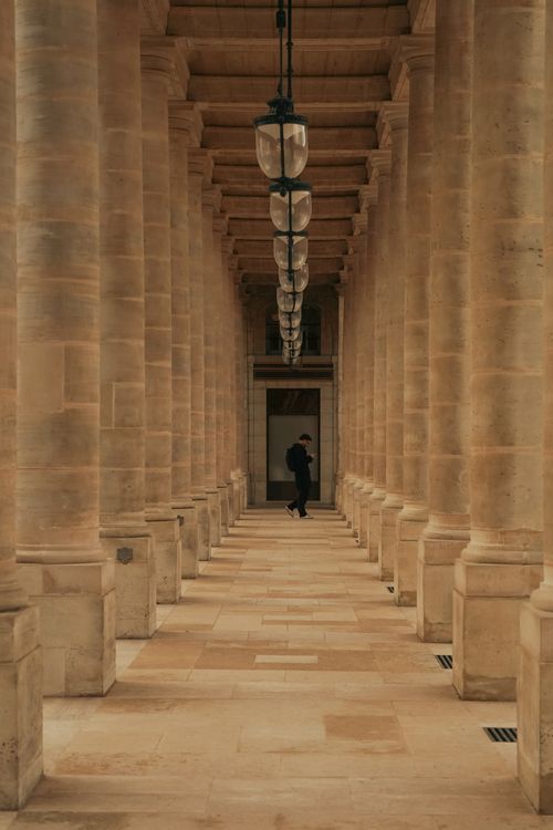 Free Stunning stone column corridor in Paris, featuring a solitary figure and elegant lighting. Stock Photo