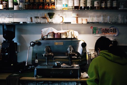 Interior of a cozy coffee shop in Beijing featuring an espresso machine and a person preparing coffee.