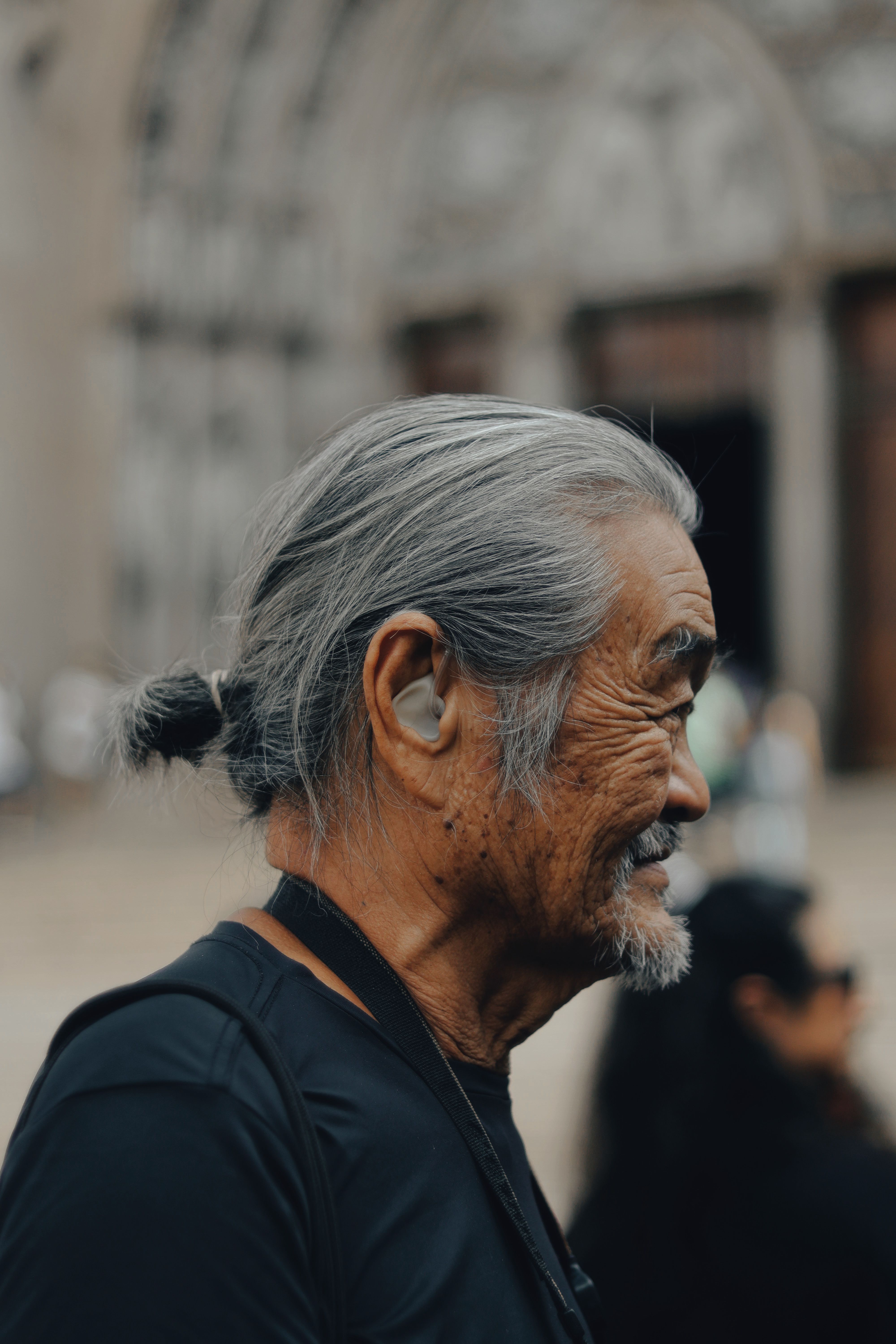 Homme senior de profil portant un appareil auditif discret dans l'oreille, en extérieur