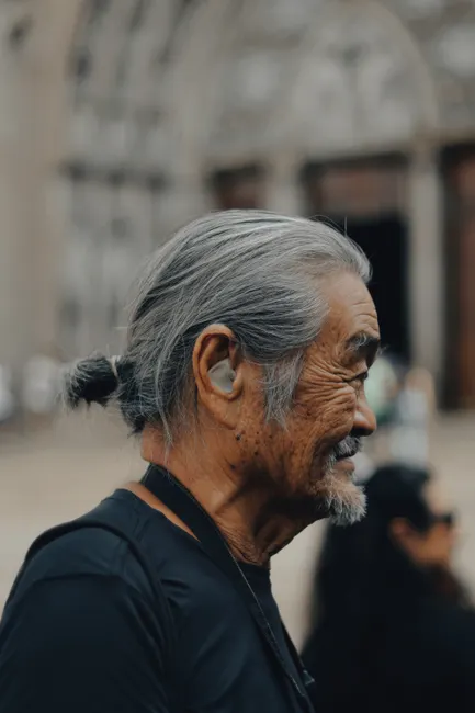Homme senior de profil portant un appareil auditif discret dans l'oreille, en extérieur