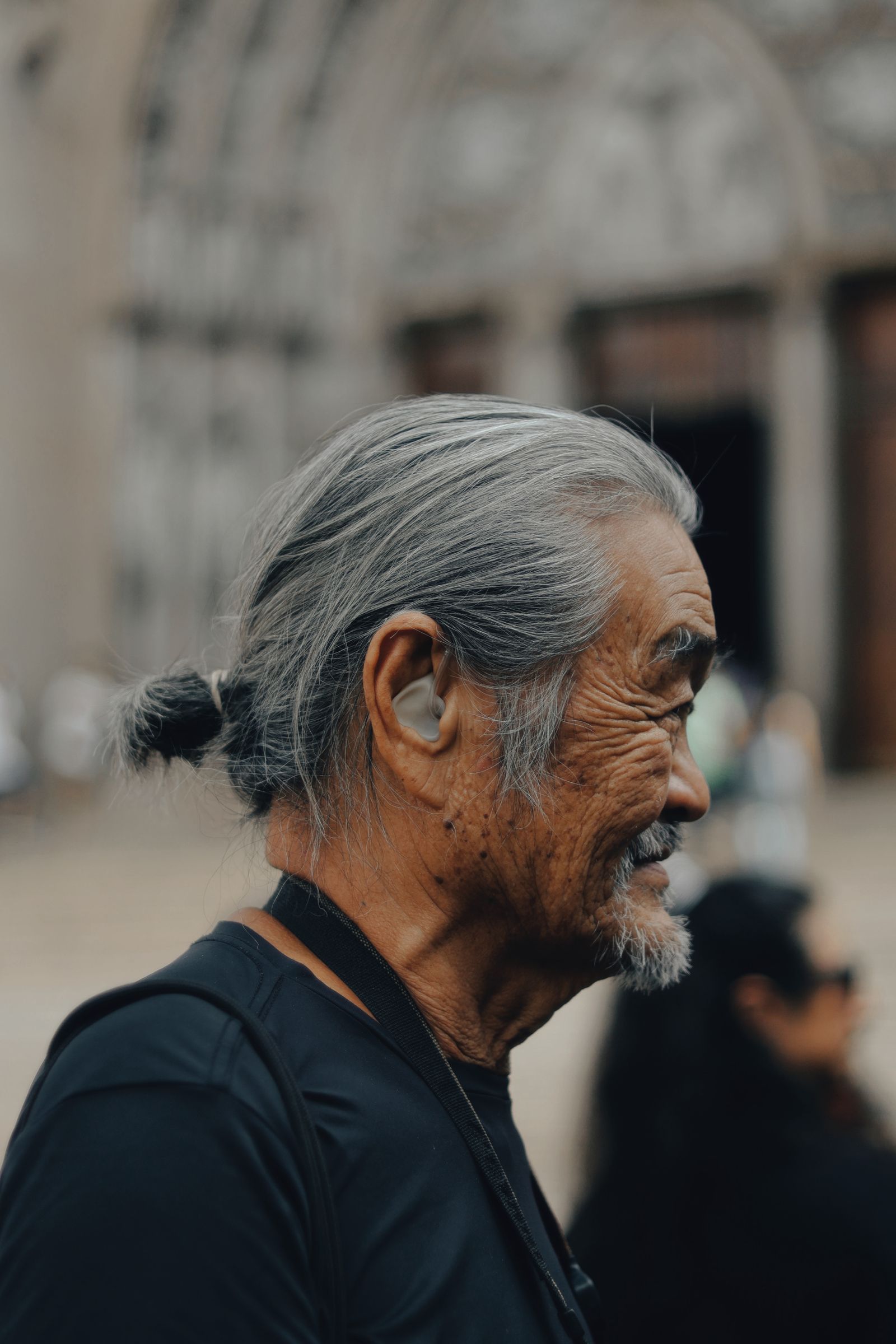 An older man in profile with a hearing aid behind his ear