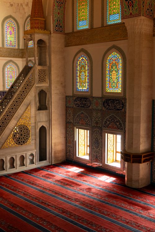 Free A beautifully lit mosque interior with intricate stained glass and ornate patterns. Stock Photo