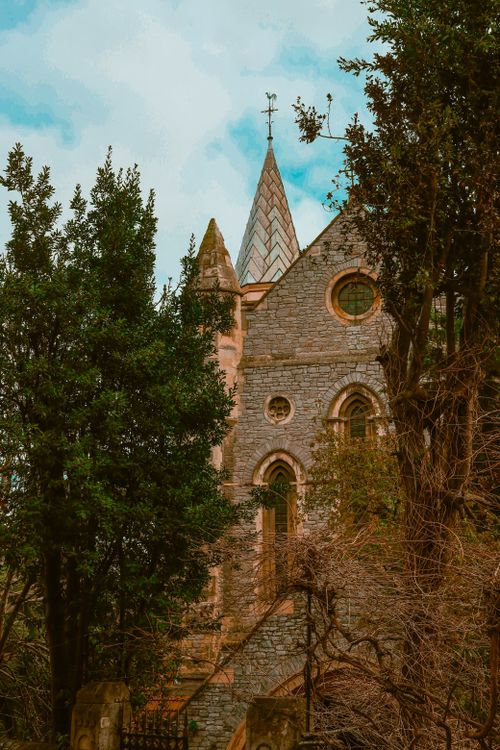 Free A charming Gothic Revival style church surrounded by dense trees, creating a serene and historical atmosphere. Stock Photo