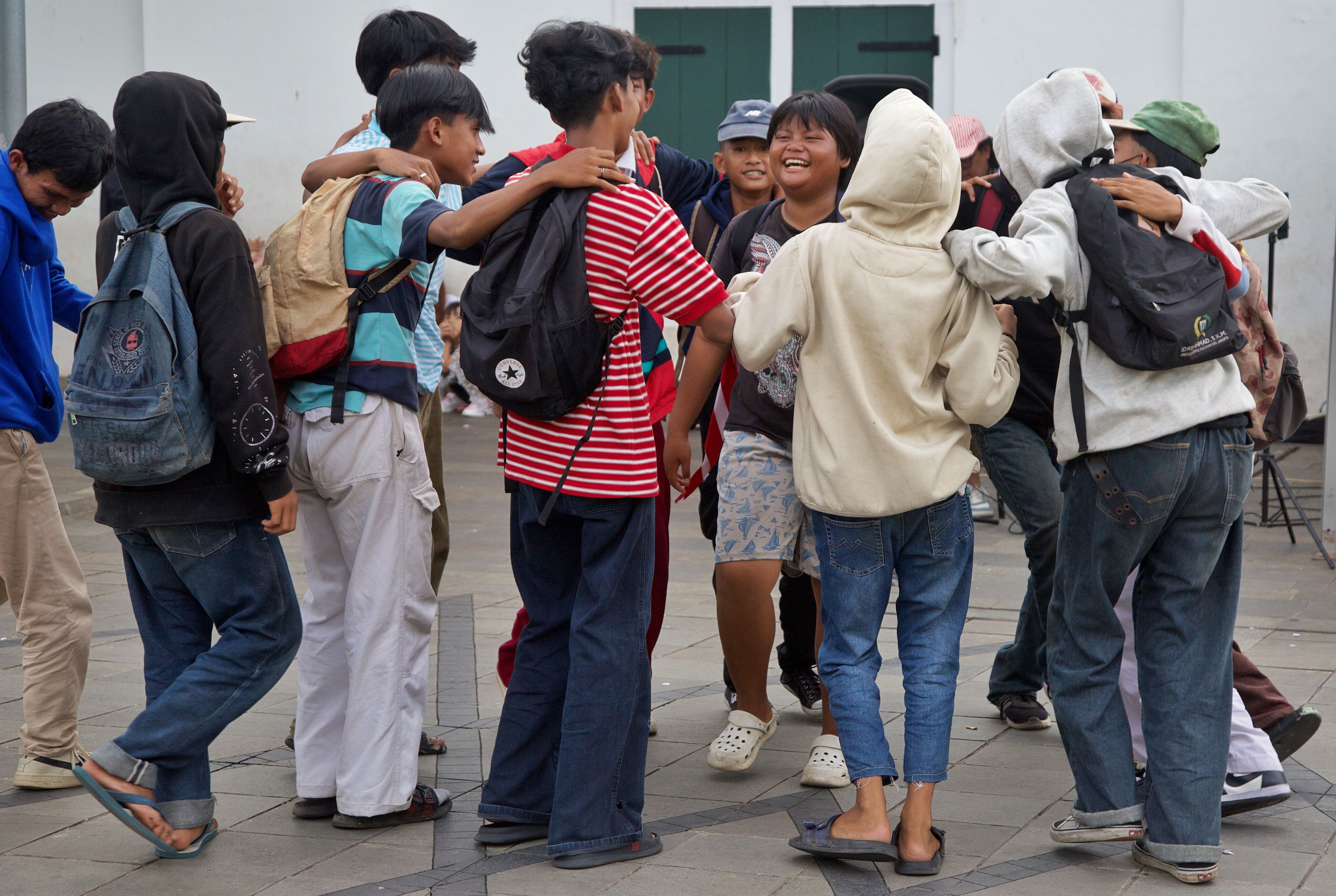 A group of teenagers laughing and interacting outdoors, showcasing friendship and joy.