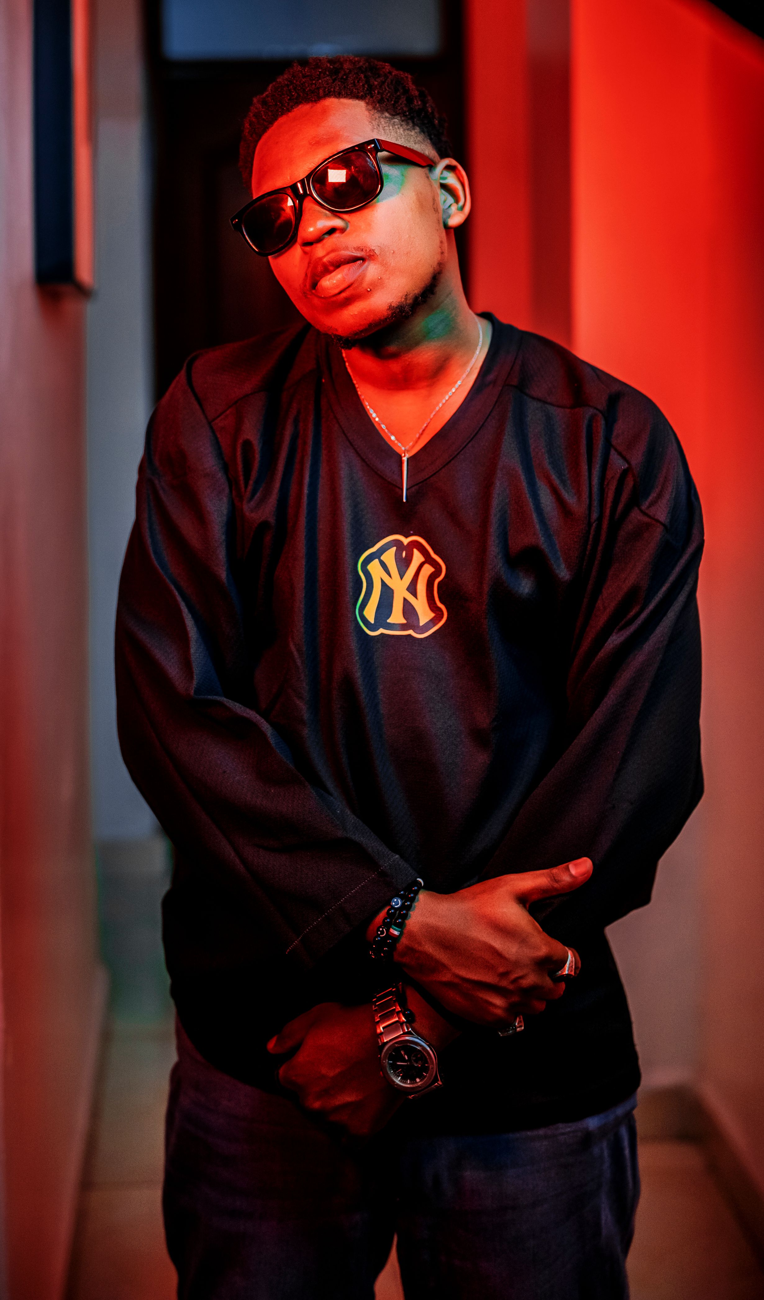 Moody portrait of a person wearing a black shirt in red neon light.