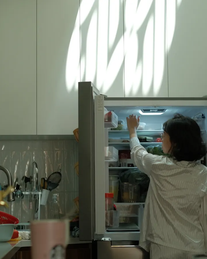 Electrolux refrigerator repair in La Mesa, CA Woman checking an open refrigerator in a warmly lit kitchen, Electrolux refrigerator repair in La Mesa