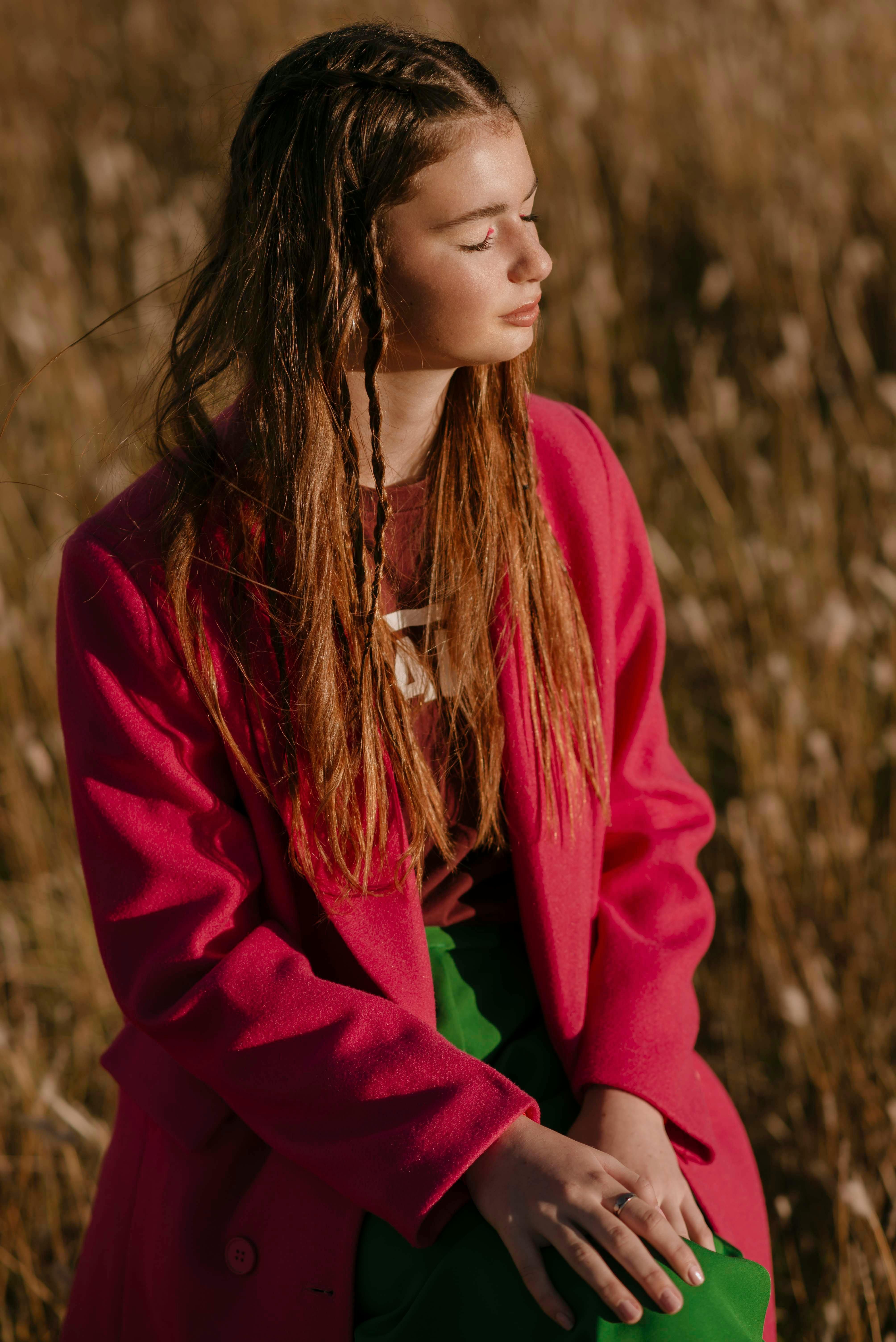 Young woman in a vibrant pink coat enjoying a sunny day outdoors in Balcarce.