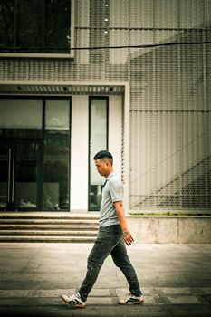 Candid shot of an Asian man walking along a contemporary street in Vietnam, showcasing urban life.