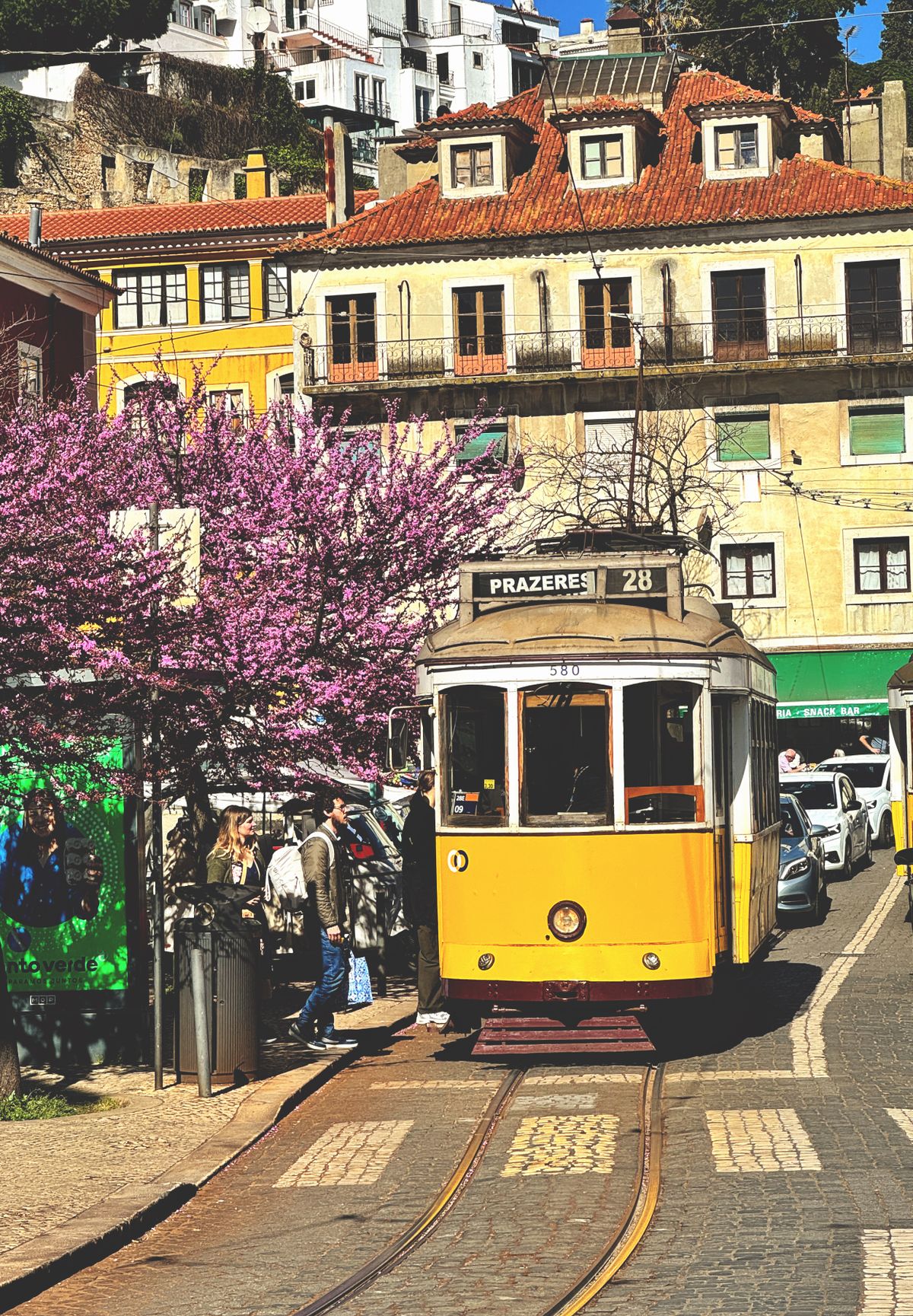 A yellow tram climbing a tiled street in Alfama, Lisbon