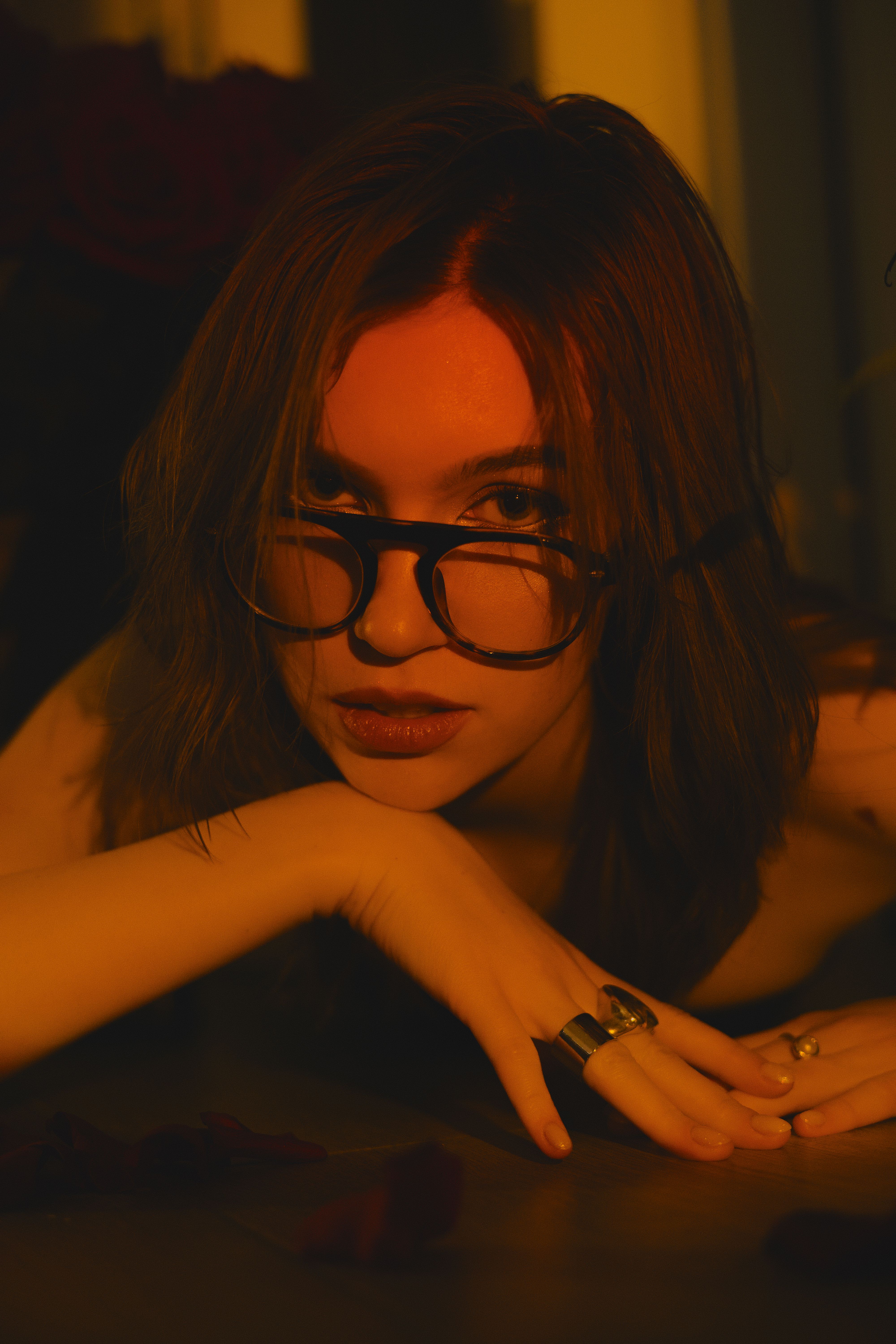 Artistic portrait of a woman with glasses in warm, dramatic light.