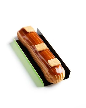 A caramel-glazed eclair with waffle toppings presented elegantly on a white background.