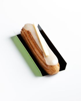 A perfectly crafted vanilla eclair topped with cream, elegantly presented in minimalist style.