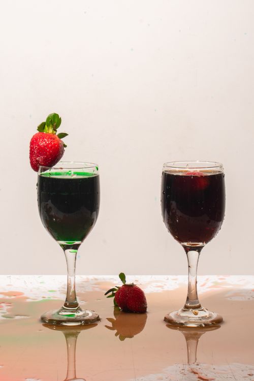 Free Two cocktail glasses with vibrant drinks and fresh strawberries on a reflective surface. Stock Photo