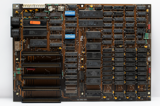 High-resolution image of an intricate vintage computer circuit board with chips and connectors.