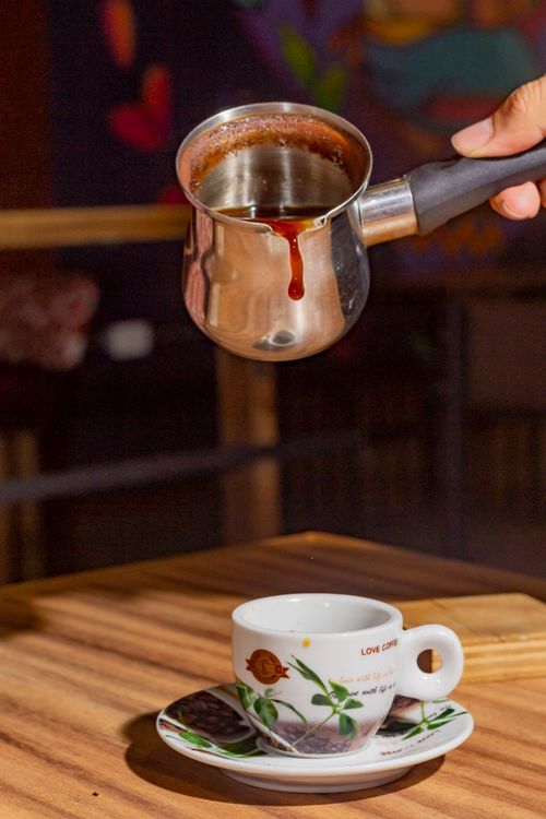Free Hand pouring Turkish coffee into a cup in a cozy café setting. Stock Photo