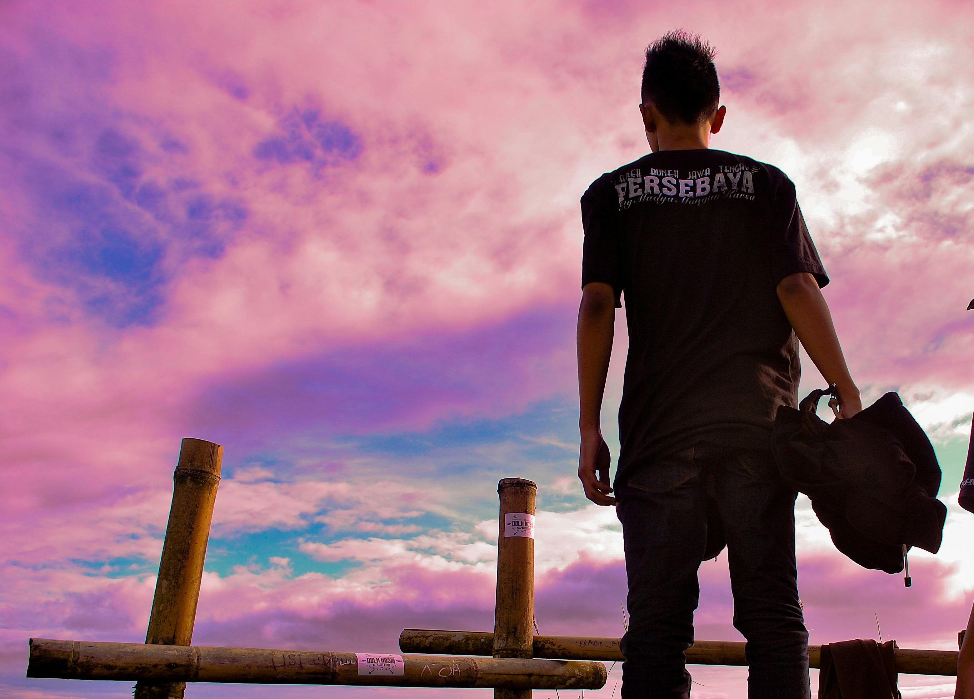 一名男子站在户外，凝视着绚丽的日落天空，营造出宁静的氛围