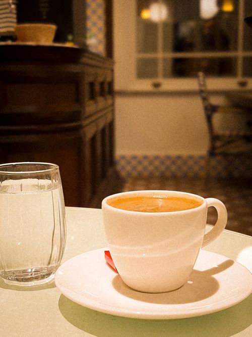 Free Warm indoor scene of a coffee cup and glass of water in a cozy cafe setting. Stock Photo