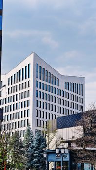 Contemporary multi-story office building exterior in Romania, framed by trees and urban landscape.